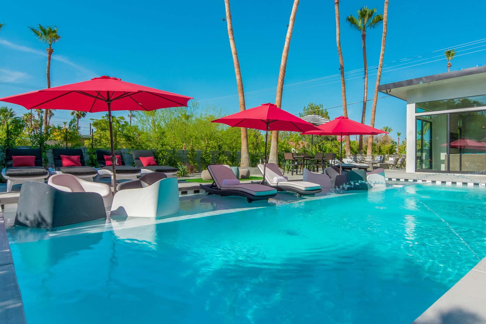 5 Palms Estate 40 by 20 foot saltwater pool with red umbrellas in daylight